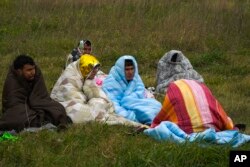 کشتی کے حادثے میں بچ جانے والے کچھ افراد نے جنوبی اٹلی کے سمندری ساحل پرسردی سے بچنے کے لیے خود کو کمبلوں سے لپیٹا ہوا ہے۔