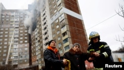 Lính cứu hỏa giúp đỡ một phụ nữ ra khỏi tòa nhà bị hư hại trong cuộc tấn công tên lửa của Nga vào Kiev, Ukraine, ngày 7/2/2024.