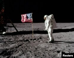 چاند کی سطح پر اترنے والے امریکی خلاباز بز ایلڈرین کی امریکی پرچم کے ساتھ چاند پر تصویر۔ چاند پر سب سے پہلا قدم نیل آرمسٹرانگ نے رکھا تھا۔ 20 جولائی 1969